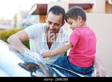 Daddys kleiner Helfer. Ein hübscher Vater und sein Sohn waschen zusammen ein Auto. Stockfoto