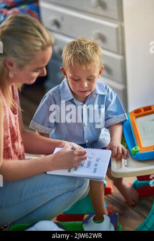 Holen Sie sich Kinder beteiligt bei der Unterstützung mit einfachen Hausarbeiten. Eine Mutter geht durch eine Liste von Aufgaben mit ihrem Sohn. Stockfoto