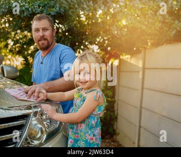 Das Auto wieder wie neu aussehen lassen. Porträt eines Vaters und einer Tochter, die zusammen ein Auto waschen. Stockfoto