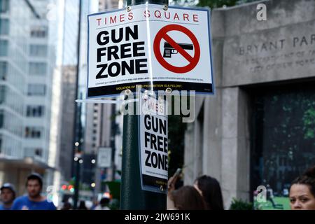 Am 3. September 2022 in New York City, USA, laufen die Menschen an einem Schild mit der Aufschrift „Gun Free Zone“ in der Nähe des Bryant Parks an einem der Zugangspunkte zum Times Square vorbei. Angesichts des jüngsten Urteils des Obersten Gerichtshofs der USA ist der Staat New York nun ein „soll-Issue“-Staat, der vorschreibt, dass jedem, der alle vorgeschriebenen Anforderungen erfüllt, keine offene oder stornierte Erlaubnis zum Tragen von Waffen verweigert werden kann. Allerdings hat der Staat New York Teile des Gesetzes geändert, in dem bestimmte Stadtteile als „Gun Free Zones“ (Foto: John Lamparski/SIPA USA) festgelegt wurden. Quelle: SIPA USA/Alamy Live News Stockfoto