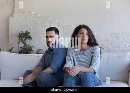 Das stille Paar sitzt auf dem Sofa und starrt nach dem Kampf zur Seite Stockfoto