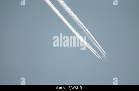 Airliner mit einem Trail hoch am blauen Himmel. Dampfspur eines Düsenflugzeugs. Reisen mit Flugzeugen. Stockfoto