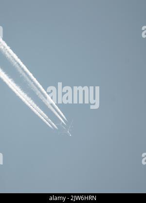 Airliner mit einem Trail hoch am blauen Himmel. Dampfspur eines Düsenflugzeugs. Reisen mit Flugzeugen. Stockfoto