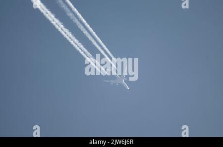 Airliner mit einem Trail hoch am blauen Himmel. Dampfspur eines Düsenflugzeugs. Reisen mit Flugzeugen. Stockfoto