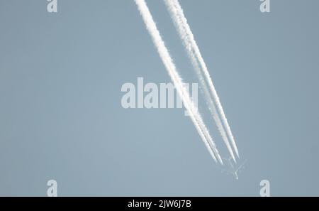 Airliner mit einem Trail hoch am blauen Himmel. Dampfspur eines Düsenflugzeugs. Reisen mit Flugzeugen. Stockfoto