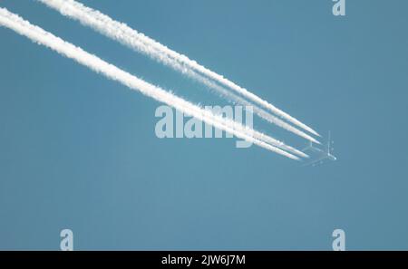 Airliner mit einem Trail hoch am blauen Himmel. Dampfspur eines Düsenflugzeugs. Reisen mit Flugzeugen. Stockfoto