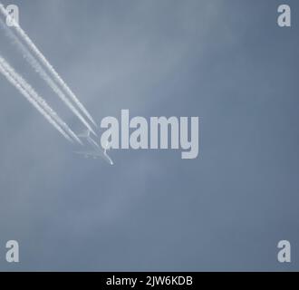 Airliner mit einem Trail hoch am blauen Himmel. Dampfspur eines Düsenflugzeugs. Reisen mit Flugzeugen. Stockfoto