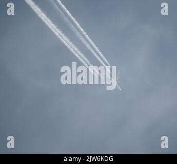 Airliner mit einem Trail hoch am blauen Himmel. Dampfspur eines Düsenflugzeugs. Reisen mit Flugzeugen. Stockfoto