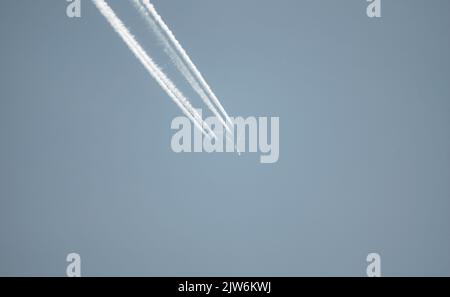 Airliner mit einem Trail hoch am blauen Himmel. Dampfspur eines Düsenflugzeugs. Reisen mit Flugzeugen. Stockfoto