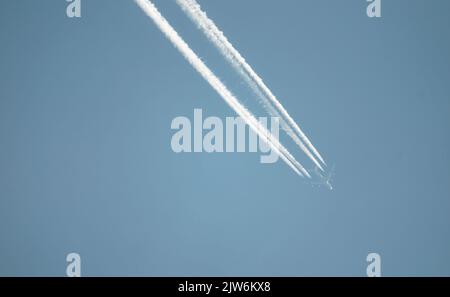 Airliner mit einem Trail hoch am blauen Himmel. Dampfspur eines Düsenflugzeugs. Reisen mit Flugzeugen. Stockfoto