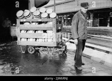 Bild eines Mitarbeiters von Van Gend & Loos mit einem Wagen mit Fässern auf der Plattform für Expressgüter der N.S. Station Utrecht et al. In Utrecht. Stockfoto