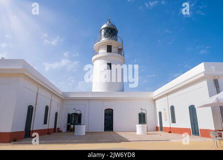 Perspektivische Ansicht eines weißen Leuchtturms an einem Sommertag mit dem blauen Himmel durch seitliche Sonnenstrahlen beleuchtet, Caballeria Leuchtturm auf Menorca, Balearen I Stockfoto