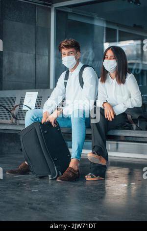 Ein spanisches Paar, das an einer Bushaltestelle eine Gesichtsmask trägt Stockfoto