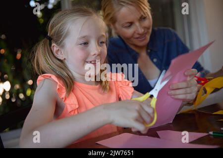 Mutter und Tochter schneiden zusammen farbige Papiere Stockfoto