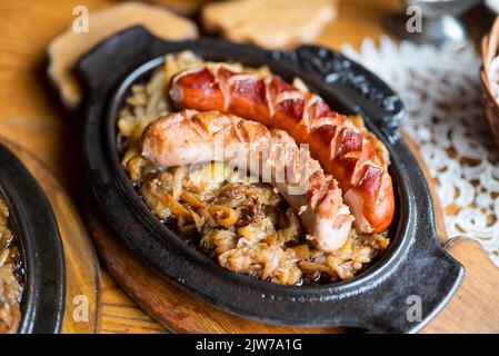 Im Restaurant werden köstliche, heiße Grillwürste mit Zwiebeln auf der Speisekarte gebacken Stockfoto