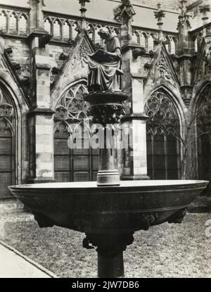 Bild des Kunstwerks von Jan Brom im Jahr 1916, das den Kanon Hugo Wstinc, den Schriftsteller des Rechtboek van de Domkerk (Mitte des 14.. Jahrhunderts), auf dem Brunnen im pandhof des Kruzifixes des Domkerk (Domplein) in Utrecht darstellt. Stockfoto