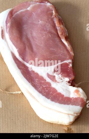 Rohe geräucherte, dick geschnittene Speckscheiben, eingewickelt in braunem Papier mit Schnur, umweltfreundliche Verpackung Stockfoto