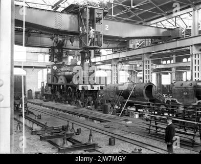 Innenraum des Depots IV der zentralen Werkstatt der H.S.M. in Haarlem: Halle 24, mit Dampflokomotive Nr. 382 der H.S.M in den Hebezeugen. (Baureihe 350-408) und rechts die demontierten Dampflokomotiven nrs. 754 (Serie 359-408, 421-460, 601-647, 701-755, 771 und 772) und 404 (Serie 350-408). Stockfoto