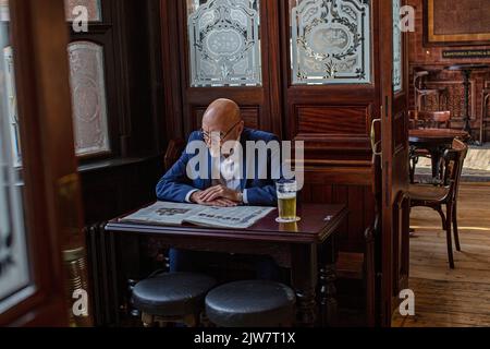 Massenschließungen von Pubs aufgrund steigender Stromrechnungen. Kundenzeitung mit einem Glas Bier in der Boleyn Tavern, West Ham, London, Großbritannien. Stockfoto