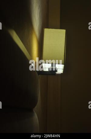 Seitenansicht der Wandleuchte in der Nähe des Bettes in der Nacht Stockfoto