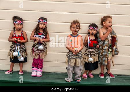 Eine kleine Gruppe von Maori-Kindern, die in ihrem traditionellen Tanzkleid gekleidet waren, beobachtete das kulturelle Tanzkonzert ihrer Eltern für Besucher des New Stockfoto