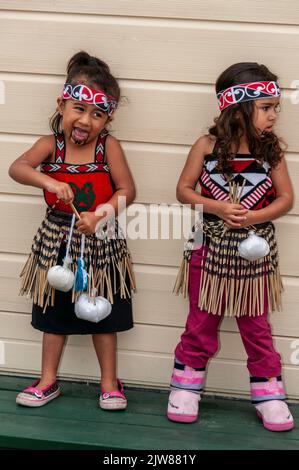 Eine kleine Gruppe von Maori-Kindern, die in ihrem traditionellen Tanzkleid gekleidet waren, beobachtete das kulturelle Tanzkonzert ihrer Eltern für Besucher des New Stockfoto