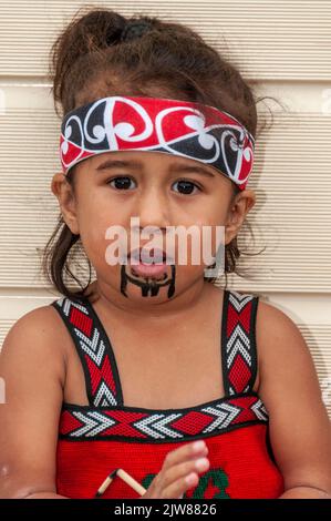 Ein Maori-Kind in ihrem traditionellen Tanzkleid, das das kulturelle Tanzkonzert ihrer Eltern für Besucher des einzigen Lebens Neuseelands besucht Stockfoto