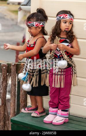 Eine kleine Gruppe von Maori-Kindern, die in ihrem traditionellen Tanzkleid gekleidet waren, beobachtete das kulturelle Tanzkonzert ihrer Eltern für Besucher des New Stockfoto