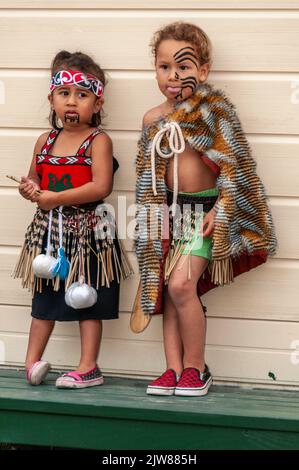 Eine kleine Gruppe von Maori-Kindern, die in ihrem traditionellen Tanzkleid gekleidet waren, beobachtete das kulturelle Tanzkonzert ihrer Eltern für Besucher des New Stockfoto