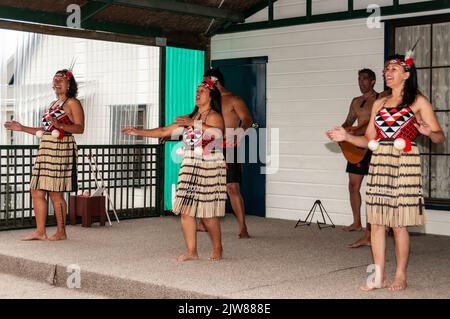 Eine Gruppe von Maori-Frauen, die bei einem Kulturkonzert für Touristen in Neuseelands einmaltem lebenden Maori-Dorf in der Geothermie auftreten Stockfoto