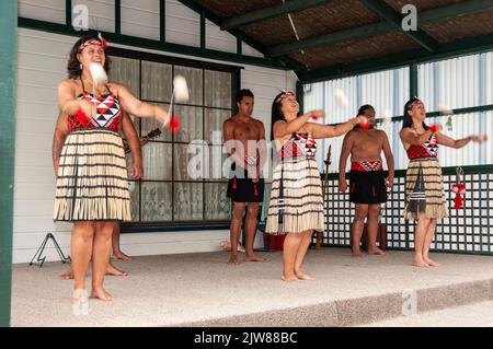 Maori-Tänzer in ihrem traditionellen Tanzkleid bei einem kulturellen Tanzkonzert für Besucher, die das einzige lebende Maori-Dorf Neuseelands besuchen Stockfoto