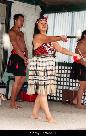 Maori-Tänzer in ihrem traditionellen Tanzkleid bei einem kulturellen Tanzkonzert für Besucher, die das einzige lebende Maori-Dorf Neuseelands besuchen Stockfoto