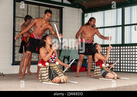 Maori-Tänzer in ihrem traditionellen Tanzkleid bei einem kulturellen Tanzkonzert für Besucher, die das einzige lebende Maori-Dorf Neuseelands besuchen Stockfoto