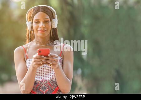 Transgender Frau, die Musik mit dem Handy im Freien hört Stockfoto