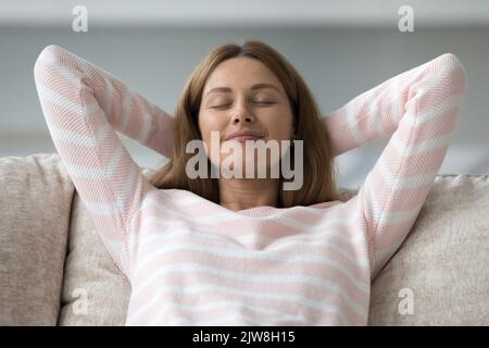 Friedliche glückliche hübsche 30s Frau, die sich auf der Couch entspannt Stockfoto