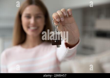 Glückliche Hauskäuferin, die die Schlüssel an der Kamera hält Stockfoto