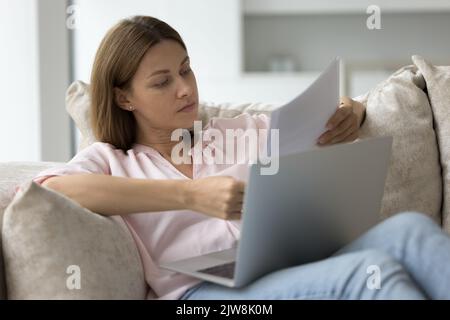 Fokussierte seriöse Millennial freiberufliche Geschäftsfrau, die Papierkram macht Stockfoto