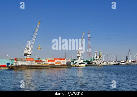 Antwerpen, Belgien - August 2022: Weitwinkelansicht von Kränen, die in den Docks der Stadt Schiffscontainer von einem Industriekahn entladen Stockfoto