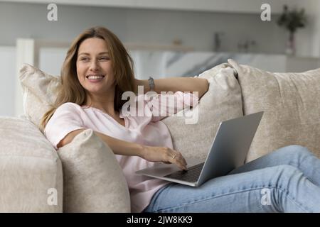 Fröhlich verträumt schöne freiberufliche Frau mit Laptop zu Hause Stockfoto