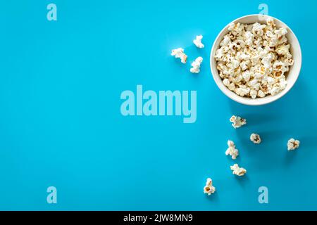 Teller mit Popcorn auf blauem Grund, flach liegend. Stockfoto
