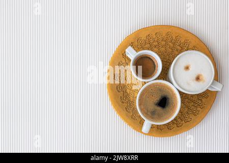 Drei Tassen Kaffee auf weißem Hintergrund, flach liegend. Stockfoto