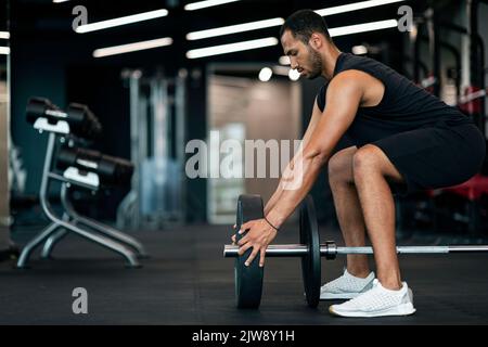 Junger Schwarzer Athlet Mit Gewichtsplatten Auf Seiner Langhantel In Gym Stockfoto