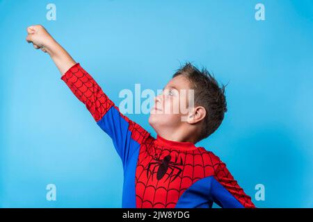 Ein Junge in einem Heldenkostüm. Eine siegreiche Aufwärtsbewegung der Hand Stockfoto