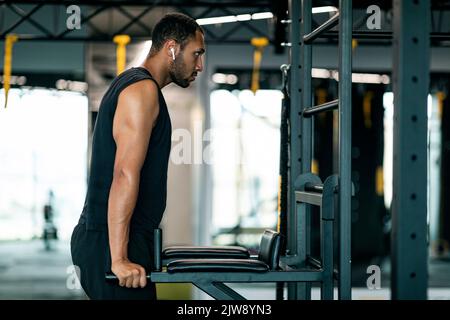 Muskulöser afroamerikanischer Mann, der parallel Bar Dips Trizeps-Übungen im Fitnessstudio macht Stockfoto