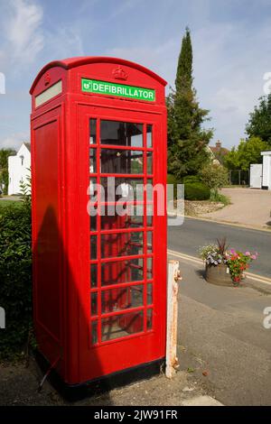 Defibrillator-Schild an der roten Telefonbox Church Road Moreton Essex Stockfoto