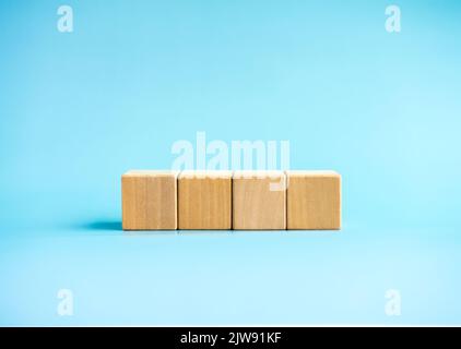 4 Holzblöcke isoliert auf blauem Hintergrund mit Kopierraum. Leere leere Vorlage Holzblock Würfel in horizontaler Reihe für Ihren Text und Nachricht angeordnet Stockfoto