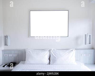 Mockup leerer weißer weißer horizontaler rechteckiger Foto- oder Kunstrahmen, der auf dem weißen Wandhintergrund über dem Bettkopf mit hängenden Lampen hängt. Moc Stockfoto