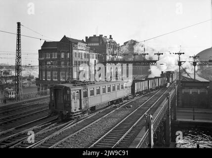 Abbildung eines Rangierwagens mit einem Wagen der elektrischen Pufferanlage („Blockboxen“, Mat. 1924) der N.S. auf der Brücke über den westlichen Zugang an der N.S. Station Amsterdam et al. (West Side) in Amsterdam. Stockfoto