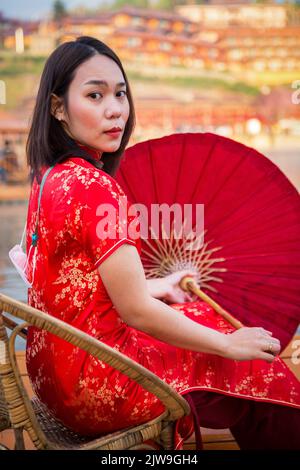 asiatische Dame Porträt entspannen in chinesischen Stil lange Kleid oder vietnam zeitgenössische Accessoires glücklich vor Ort Morgen Stockfoto