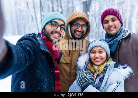 Vier Personen, die an den Feiertagen im Freien Selfie machen Stockfoto